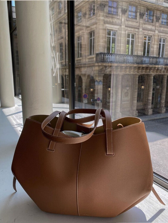 Borsa a mano in pelle marrone su sfondo urbano, design elegante e moderno, perfetta per moda donna, accessori di lusso, shopping e ufficio.