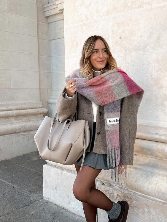 Donna con cappotto beige, sciarpa a quadri rosa e borsa a mano beige, posa all'aperto. Moda autunnale, abbigliamento casual elegante.