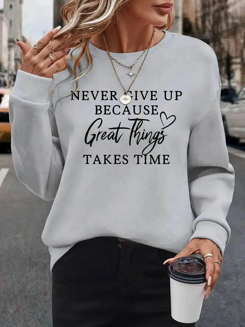 Donna con felpa grigia con scritta motivazionale, collane dorate e caffè in mano. Moda casual autunnale, abbigliamento street style.