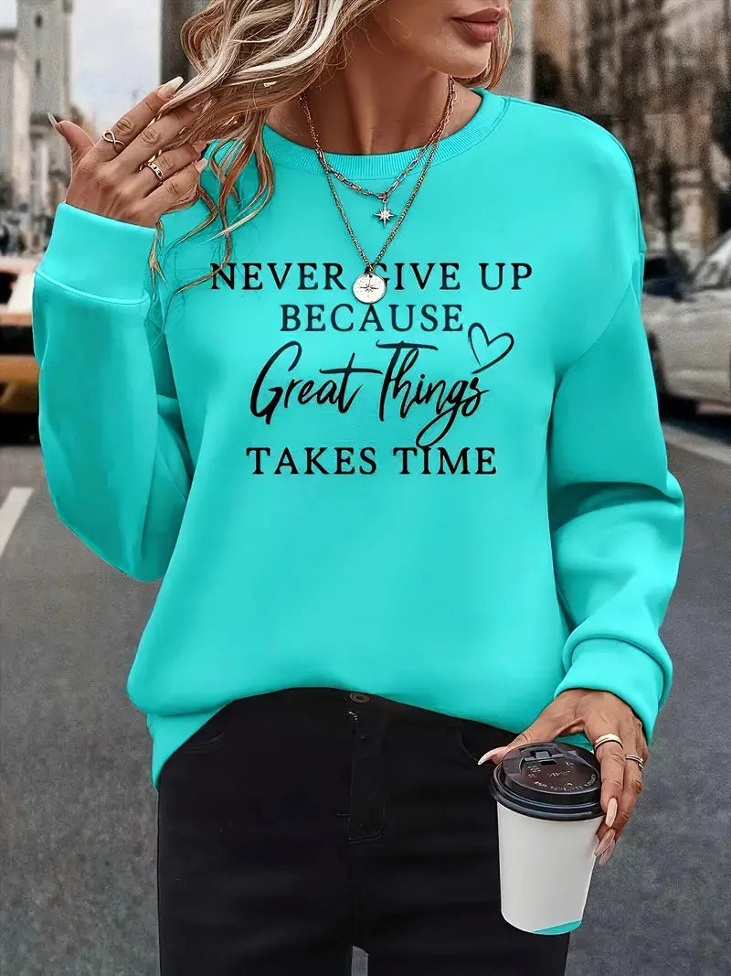 Donna con felpa turchese con scritta motivazionale, collane dorate e caffè da asporto. Moda casual, abbigliamento autunnale, ispirazione quotidiana.