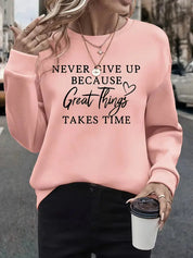 Donna con felpa rosa con scritta motivazionale, collane dorate, e caffè da asporto. Moda casual autunnale, abbigliamento streetwear femminile.