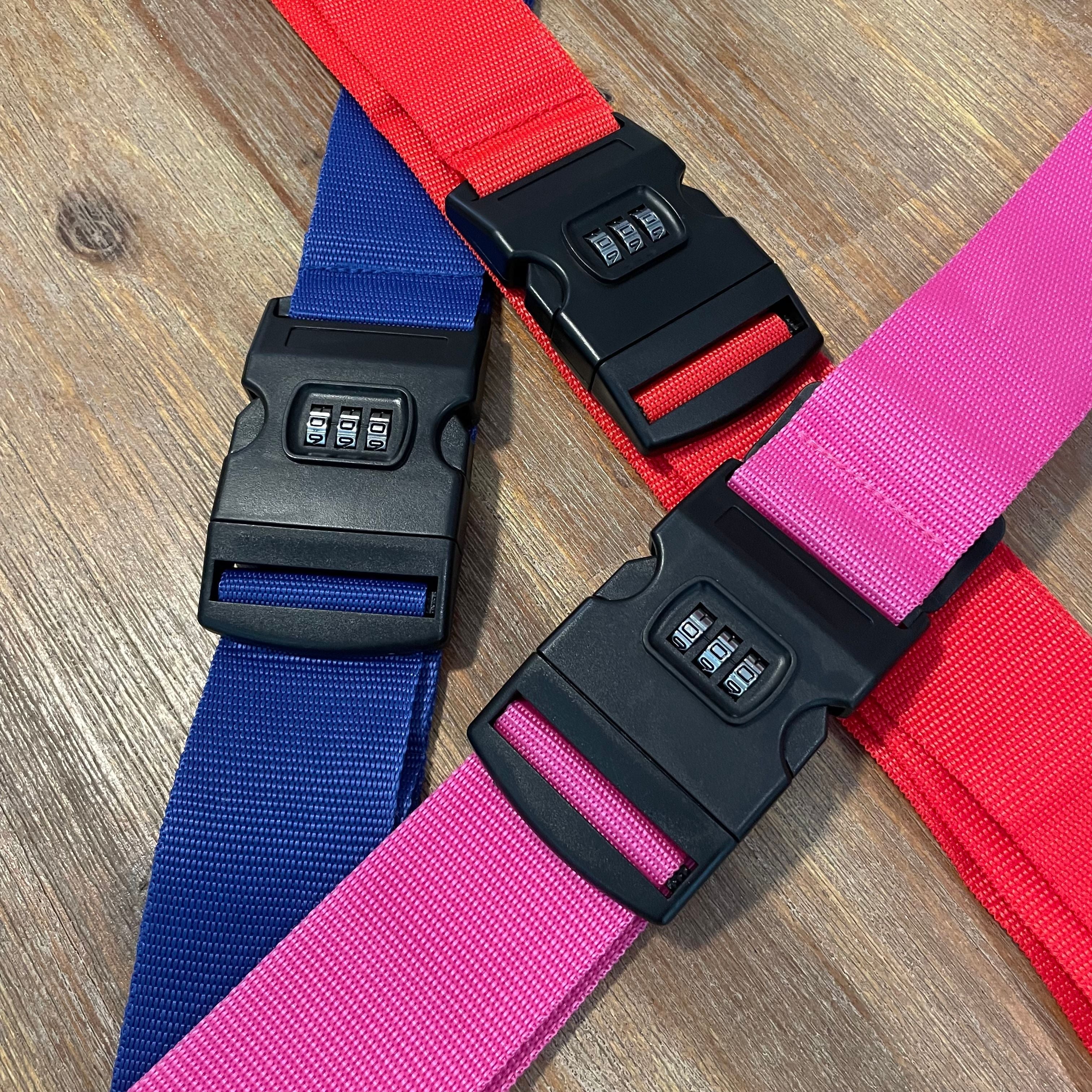 Cinghie bagaglio colorate con chiusura a combinazione numerica, blu, rosso e rosa, su sfondo in legno. Accessori viaggio sicuri e regolabili.