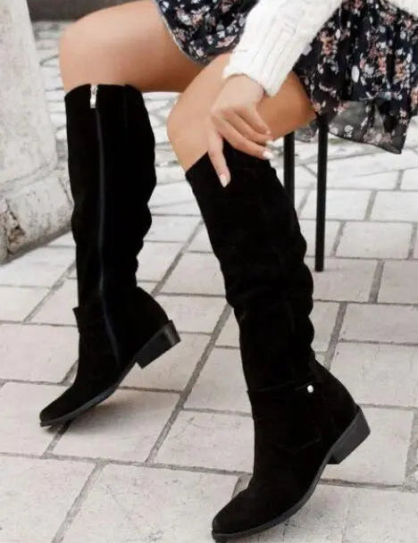 Stivali alti neri in pelle scamosciata, indossati con abito floreale e maglione bianco. Moda autunnale donna, calzature eleganti.