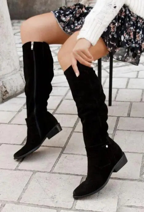 Stivali alti neri in pelle scamosciata, indossati con abito floreale e maglione bianco. Moda autunnale donna, calzature eleganti.