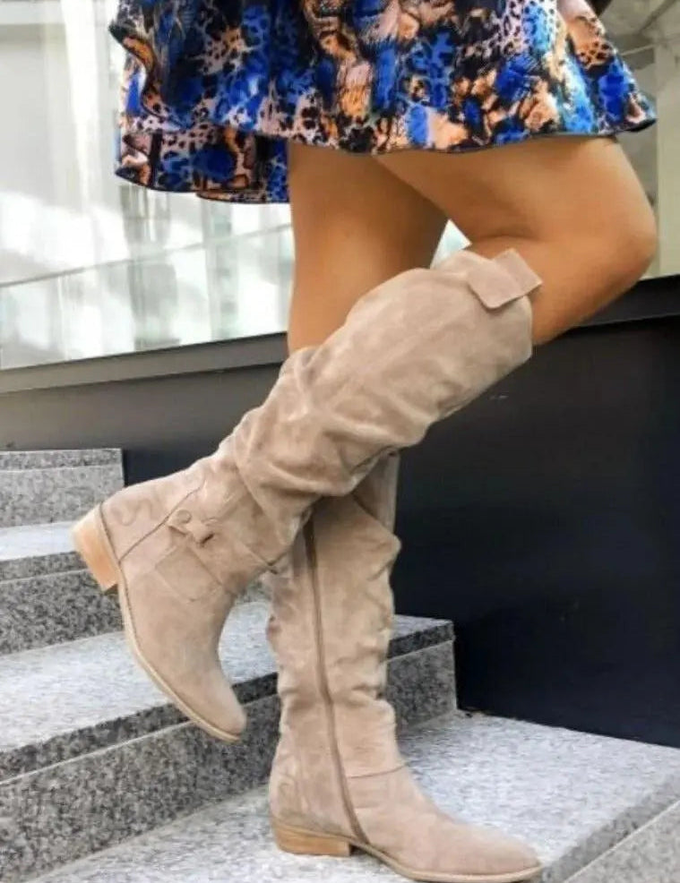 Stivali alti beige in camoscio su gradini, abbinati a gonna colorata. Scarpe moda donna, stile autunnale, tacco basso, eleganti e casual.