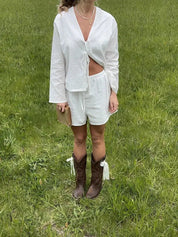 Donna in abito bianco estivo con stivali da cowboy marroni su prato verde. Moda casual, look estivo, abbigliamento femminile trendy.