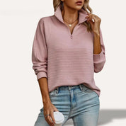 Donna con maglione rosa a coste con zip, jeans chiari, tiene una tazza da caffè. Moda casual autunnale, abbigliamento femminile trendy.
