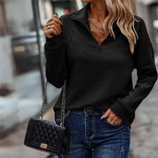 Donna con maglione nero a coste, jeans blu e borsa a tracolla trapuntata nera. Look casual chic, moda autunnale, stile urbano elegante.