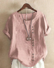 Camicia donna in lino rosa con bottoni decorativi, maniche corte risvolte, abbinata a collana pendente. Stile casual elegante.