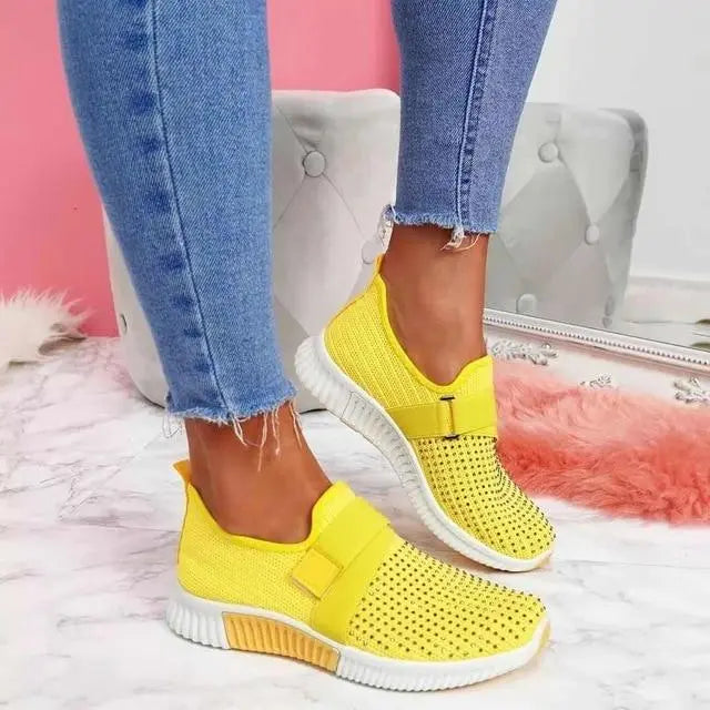 Scarpe da ginnastica gialle da donna, design traspirante, suola bianca, indossate con jeans. Scarpe casual moda, comode per passeggiate.