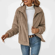 Giacca in pelliccia sintetica beige da donna, stile casual, con collo alto, abbinata a maglione bianco e jeans. Moda autunno inverno.