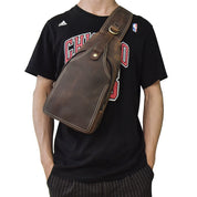Borsa a tracolla in pelle marrone su uomo con maglietta sportiva nera. Accessorio moda maschile, stile casual, ideale per viaggi e uso quotidiano.