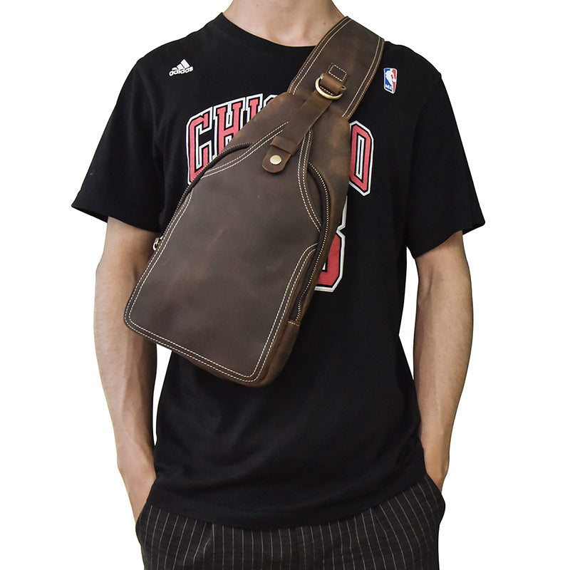 Borsa a tracolla in pelle marrone su uomo con maglietta sportiva nera. Accessorio moda maschile, stile casual, ideale per viaggi e uso quotidiano.
