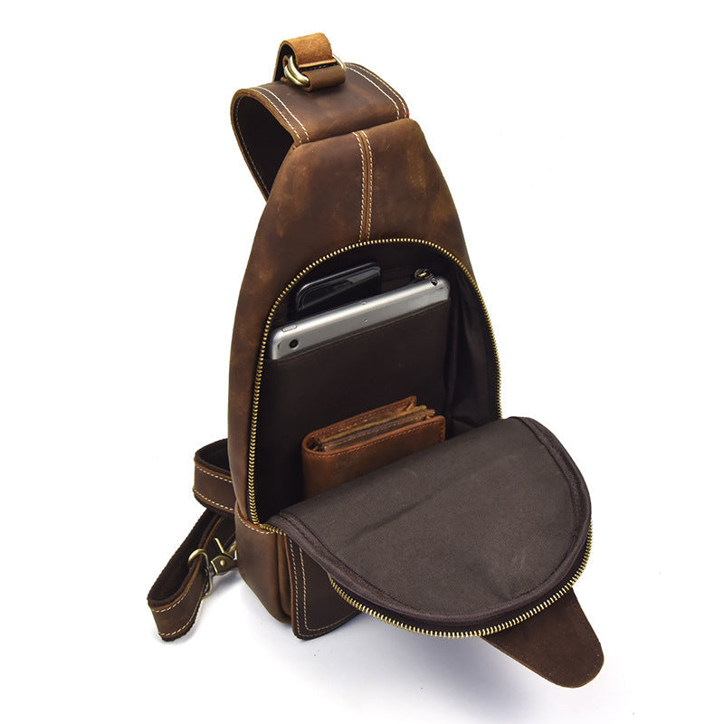 Zaino monospalla in pelle marrone con tasca aperta, mostra tablet e portafoglio. Design elegante, ideale per viaggi e uso quotidiano.