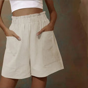 Shorts beige a vita alta con tasche grandi, indossati da una persona con top bianco. Stile casual estivo, moda donna, abbigliamento comodo.