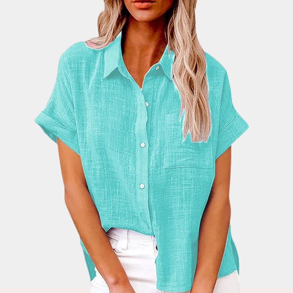 Camicia donna estiva azzurra, maniche corte, tessuto leggero, colletto classico, abbinata a pantaloni bianchi. Moda casual elegante.