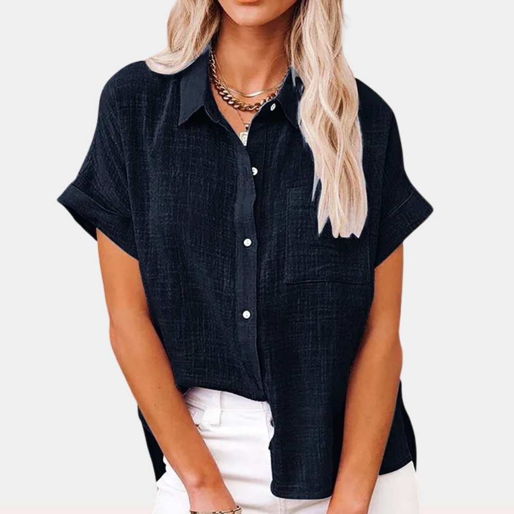 Camicia donna nera a maniche corte, tessuto leggero, colletto classico, abbinata a pantaloni bianchi. Stile casual elegante, moda estiva.