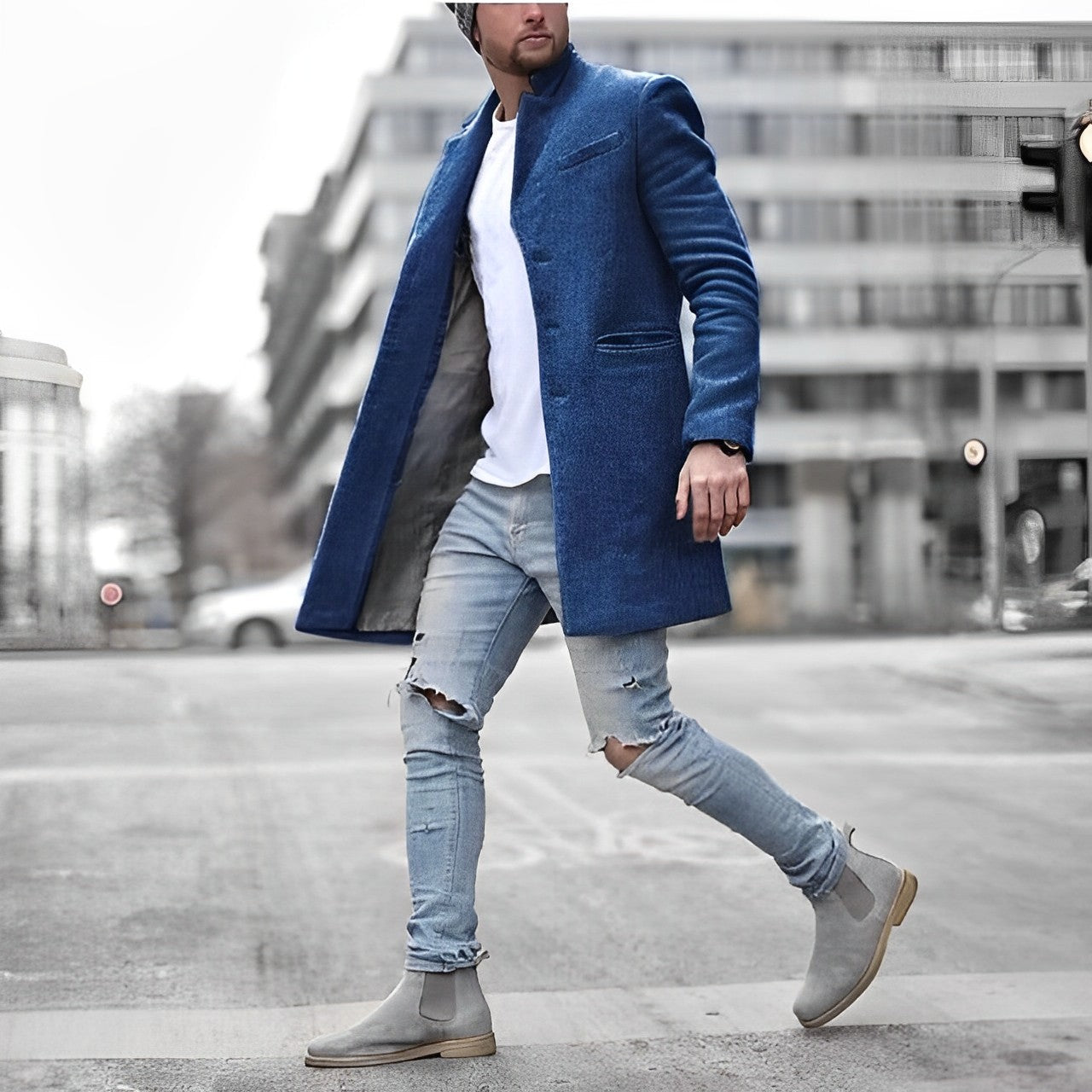 Uomo con cappotto blu elegante, jeans strappati e stivali grigi cammina in città. Moda maschile urbana, abbigliamento invernale trendy.
