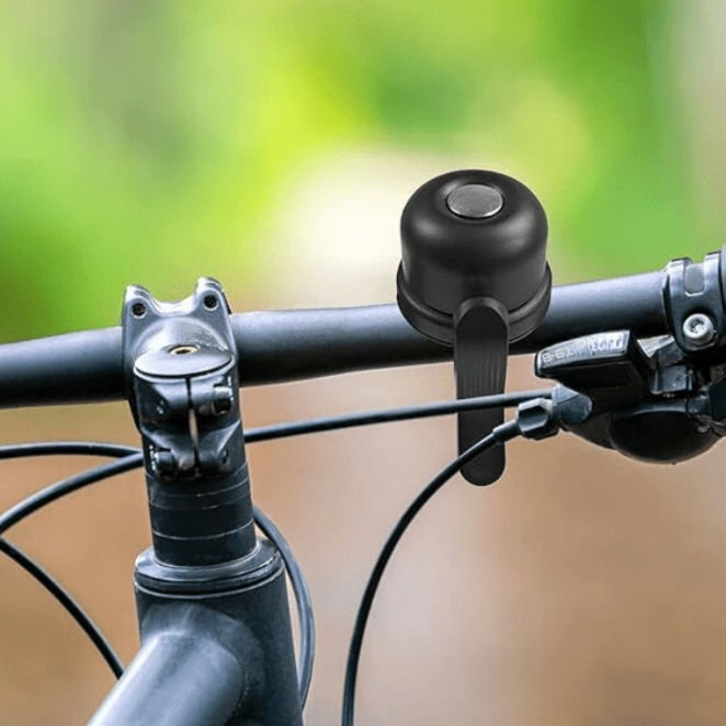 Campanello per bicicletta nero su manubrio, primo piano. Accessorio essenziale per sicurezza ciclistica, compatibile con vari modelli di bici.
