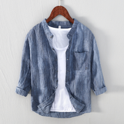 Camicia di lino blu da uomo su gruccia, design casual con colletto alla coreana, abbinata a t-shirt bianca. Moda estiva, abbigliamento leggero.
