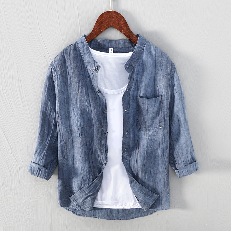 Camicia di lino blu da uomo su gruccia, design casual con colletto alla coreana, abbinata a t-shirt bianca. Moda estiva, abbigliamento leggero.