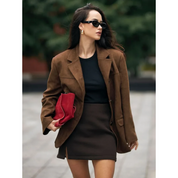 Donna con giacca marrone, occhiali da sole e borsa rossa. Moda autunnale elegante, abbigliamento casual chic, tendenze street style.