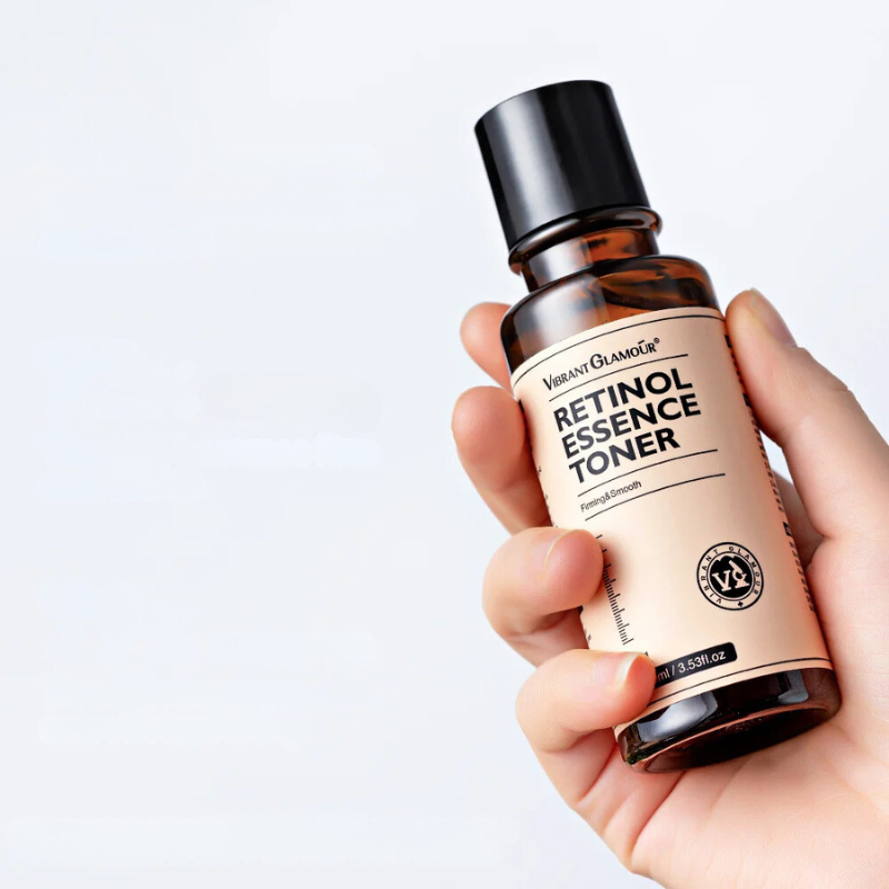 Bottiglia di tonico al retinolo Vibrant Glamour tenuta in mano, etichetta visibile. Skincare, anti-invecchiamento, cura della pelle, cosmetici.