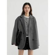 Giacca donna grigia oversize, elegante e moderna, con bottoni neri. Indossata con borsa a catena e abbigliamento casual. Moda autunno inverno.