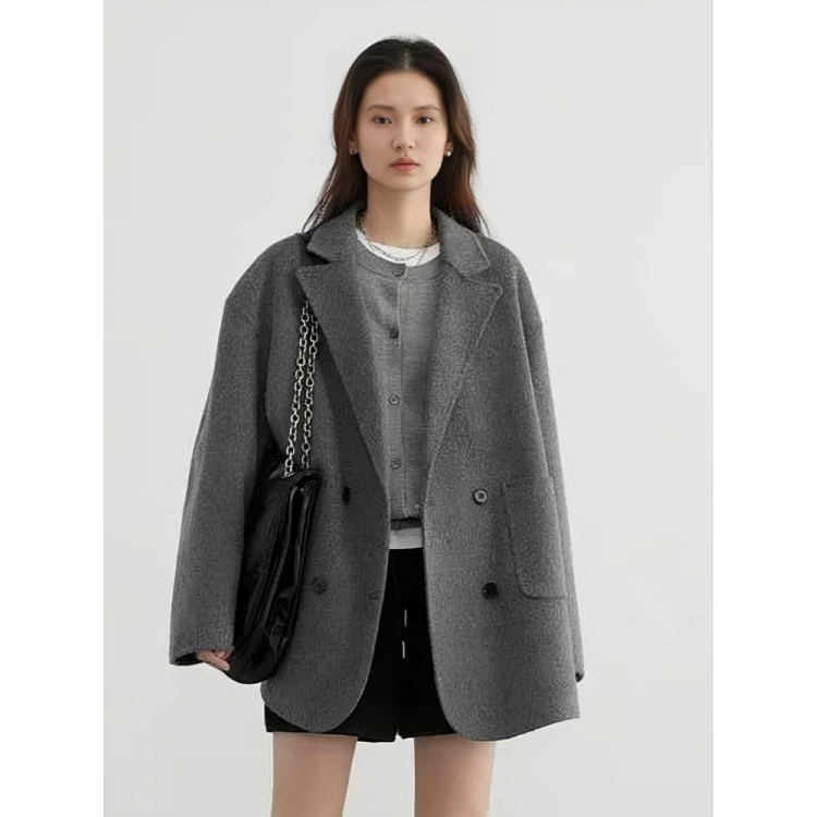 Giacca donna grigia oversize, elegante e moderna, con bottoni neri. Indossata con borsa a catena e abbigliamento casual. Moda autunno inverno.