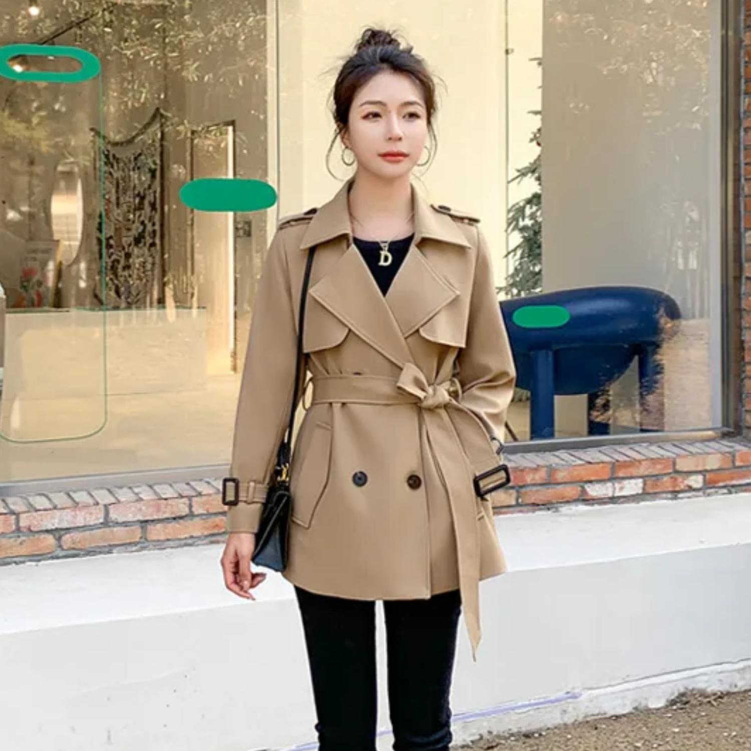 Giacca trench beige da donna, doppio petto, cintura in vita, stile elegante, perfetta per l'autunno. Sfondo urbano con vetrina.