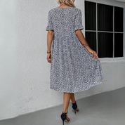 Abito estivo donna floreale blu e bianco, maniche corte, lunghezza al ginocchio, indossato con tacchi neri. Elegante e casual per ogni occasione.