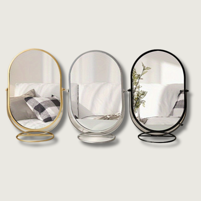 Tre specchi ovali da tavolo con cornici in metallo dorato, argento e nero, riflettono un divano bianco e cuscini a quadri. Design moderno ed elegante.