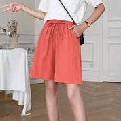 Shorts donna arancioni in lino, vita alta con laccio, abbinati a maglietta bianca. Moda estiva casual, outfit comodo e trendy.