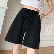 Shorts neri da donna a vita alta con elastico e laccio, abbinati a top bianco corto. Moda estiva casual, abbigliamento comodo e trendy.