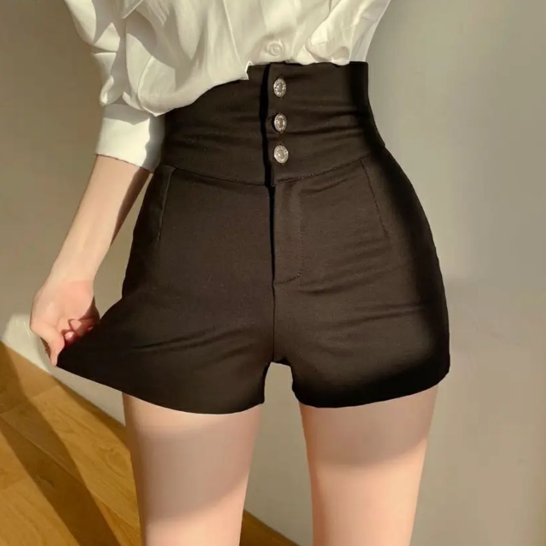 Pantaloncini neri a vita alta con bottoni, indossati da una donna in camicia bianca. Moda femminile elegante, abbigliamento casual chic.
