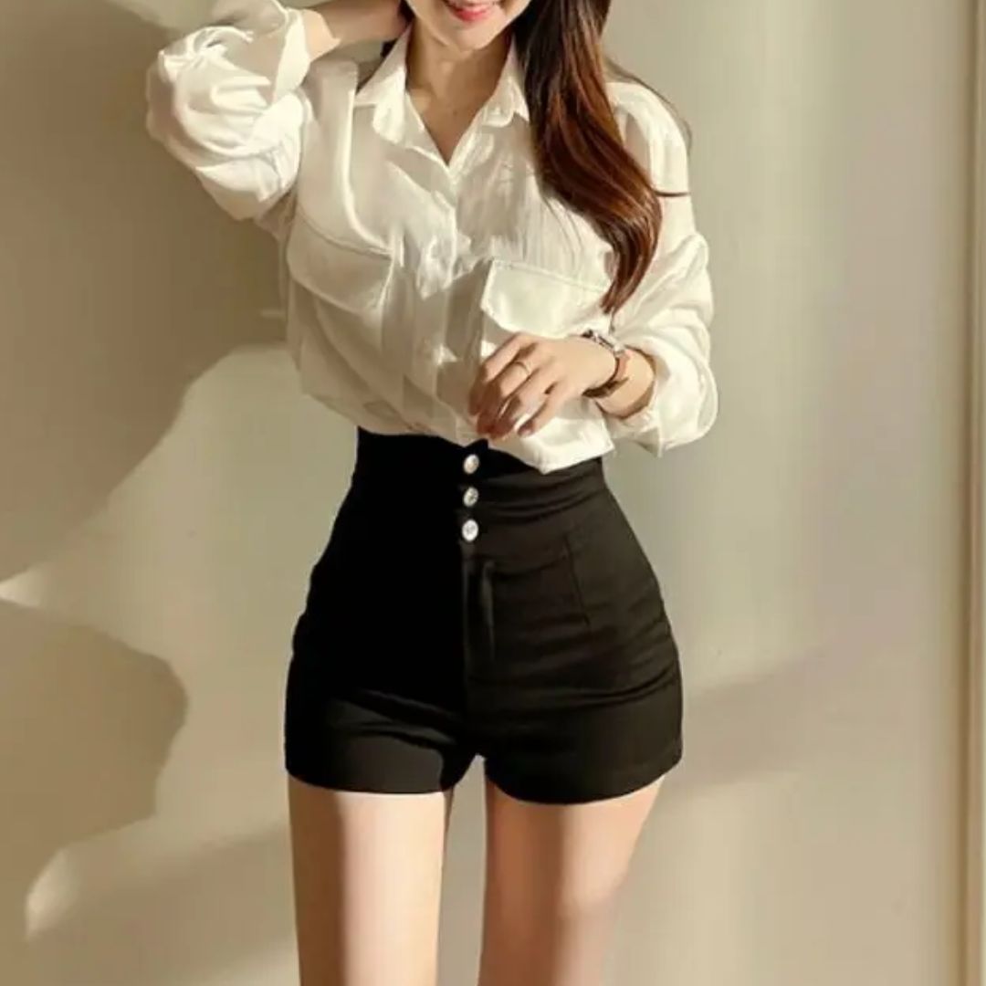 Donna in camicia bianca e pantaloncini neri a vita alta, moda casual elegante, abbigliamento femminile trendy, outfit estivo alla moda.