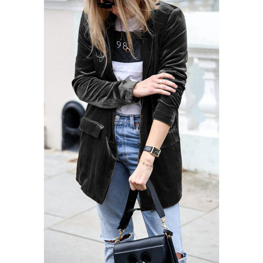 Donna con giacca di velluto nera, jeans strappati e borsa a tracolla nera. Look casual chic, moda autunnale, street style femminile.
