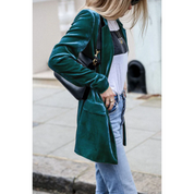 Donna con giacca di velluto verde, jeans chiari e borsa nera a tracolla. Moda urbana, stile casual chic, abbigliamento autunnale.