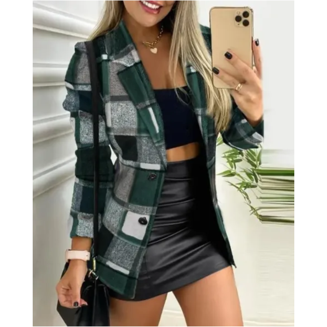 Donna con blazer a quadri verde, top nero e gonna in pelle, scatta selfie con smartphone. Moda autunnale, outfit elegante e casual.