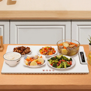 Piatto riscaldante elettrico su tavolo da cucina con ciotole di riso, stufato di carne, verdure miste e insalata, ideale per mantenere il cibo caldo.