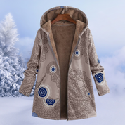 Cappotto invernale con cappuccio, motivo geometrico beige e blu, interno in pelliccia sintetica, appeso su sfondo innevato. Moda donna, abbigliamento caldo.