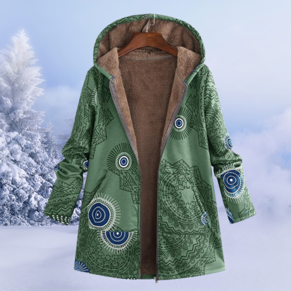 Cappotto invernale verde con cappuccio, motivo geometrico, foderato in pelliccia sintetica, appeso su gruccia, sfondo innevato.