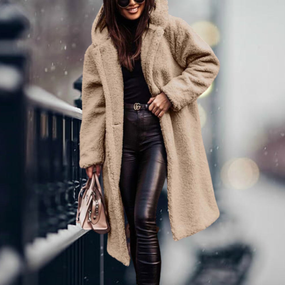 Donna con cappotto teddy beige, pantaloni in pelle nera e borsa a mano, cammina in città invernale. Moda invernale, cappotto caldo, stile urbano.