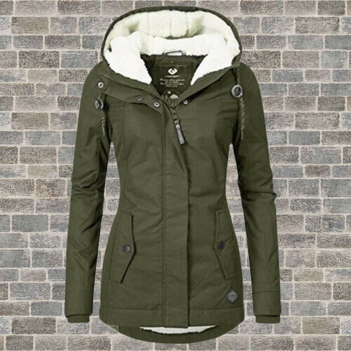 Giacca invernale verde oliva da donna con cappuccio foderato in pelliccia sintetica, chiusura a zip e bottoni, su sfondo di mattoni grigi.