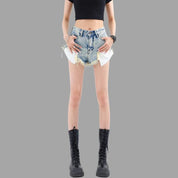 Donna in pantaloncini di jeans strappati e stivali neri, top corto nero. Moda estiva casual, abbigliamento giovanile trendy. Sfondo grigio.