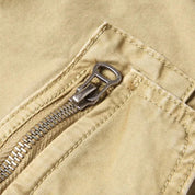 Cerniera lampo in metallo su tessuto beige, dettaglio di pantaloni casual. Moda uomo, abbigliamento estivo, stile urbano.