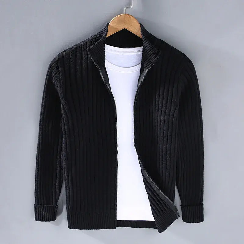 Giacca cardigan nero a coste con zip, appesa su gruccia, sopra maglietta bianca. Moda uomo, abbigliamento casual, stile autunnale.