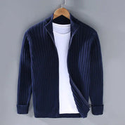 Cardigan blu scuro a coste con zip, appeso su gruccia, sopra maglietta bianca. Moda uomo, abbigliamento casual elegante, tessuto caldo.