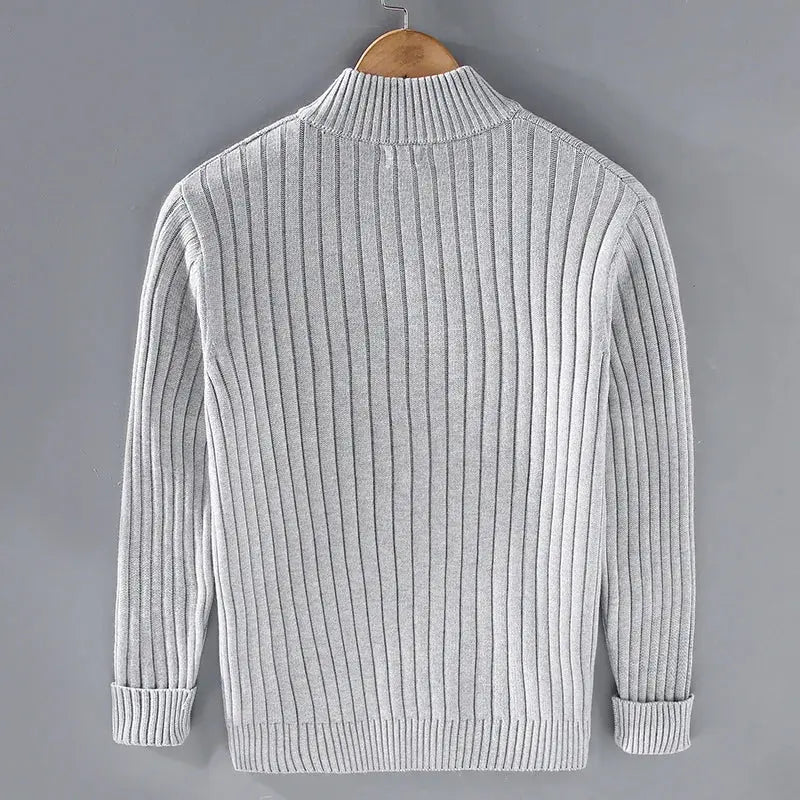 Maglione grigio a coste, maniche lunghe, collo alto, su gruccia. Design elegante e caldo, ideale per moda autunno-inverno uomo.