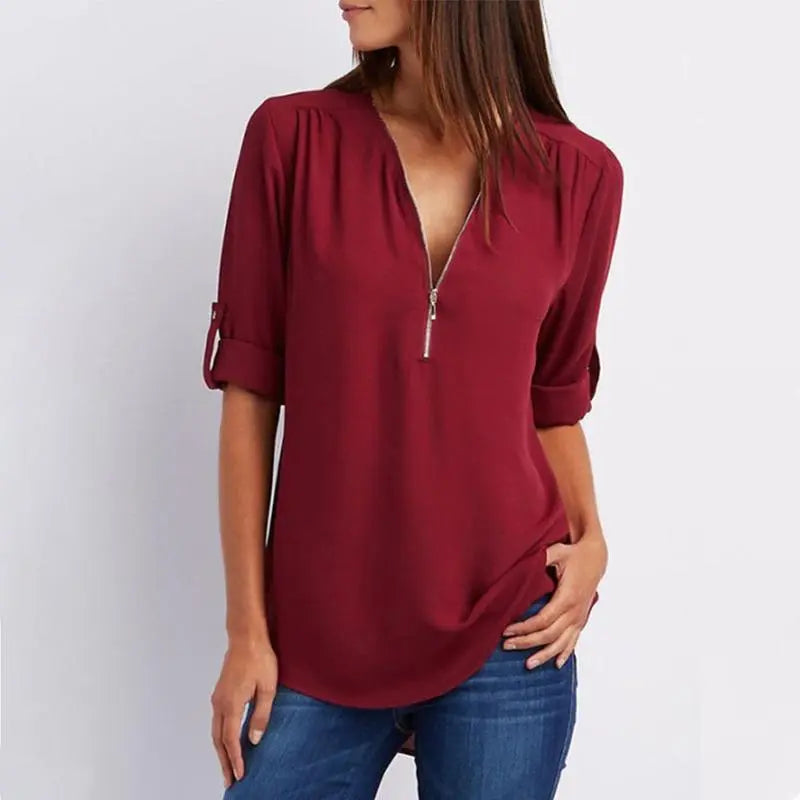 Donna con blusa bordeaux a maniche lunghe, scollo a V con zip, abbinata a jeans. Moda casual femminile, abbigliamento autunnale elegante.